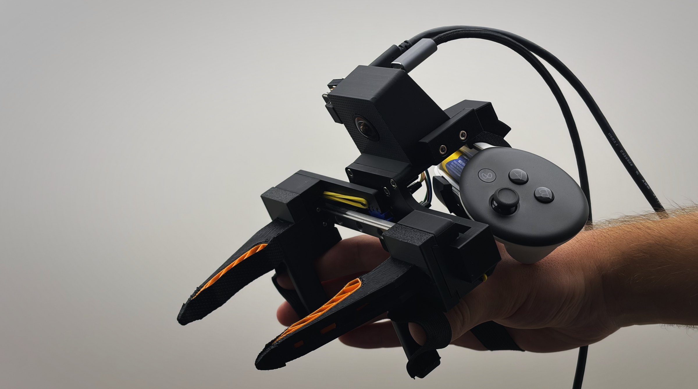 The UMI gripper held in a hand, with the Quest controller and the wrist camera mounted on top.