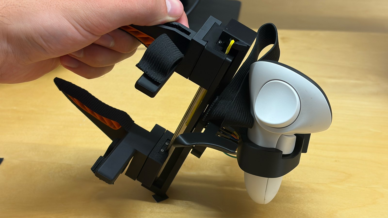 The gripper held by hand and tilted, with one corner of its mount pressed onto the table.