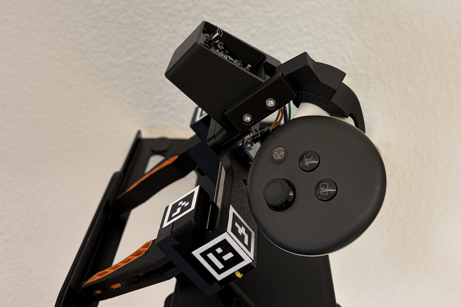 The UMI gripper standing tilted on a rig, the Quest controller mounted on it, with square ArUco tags glued to faces of the mount.